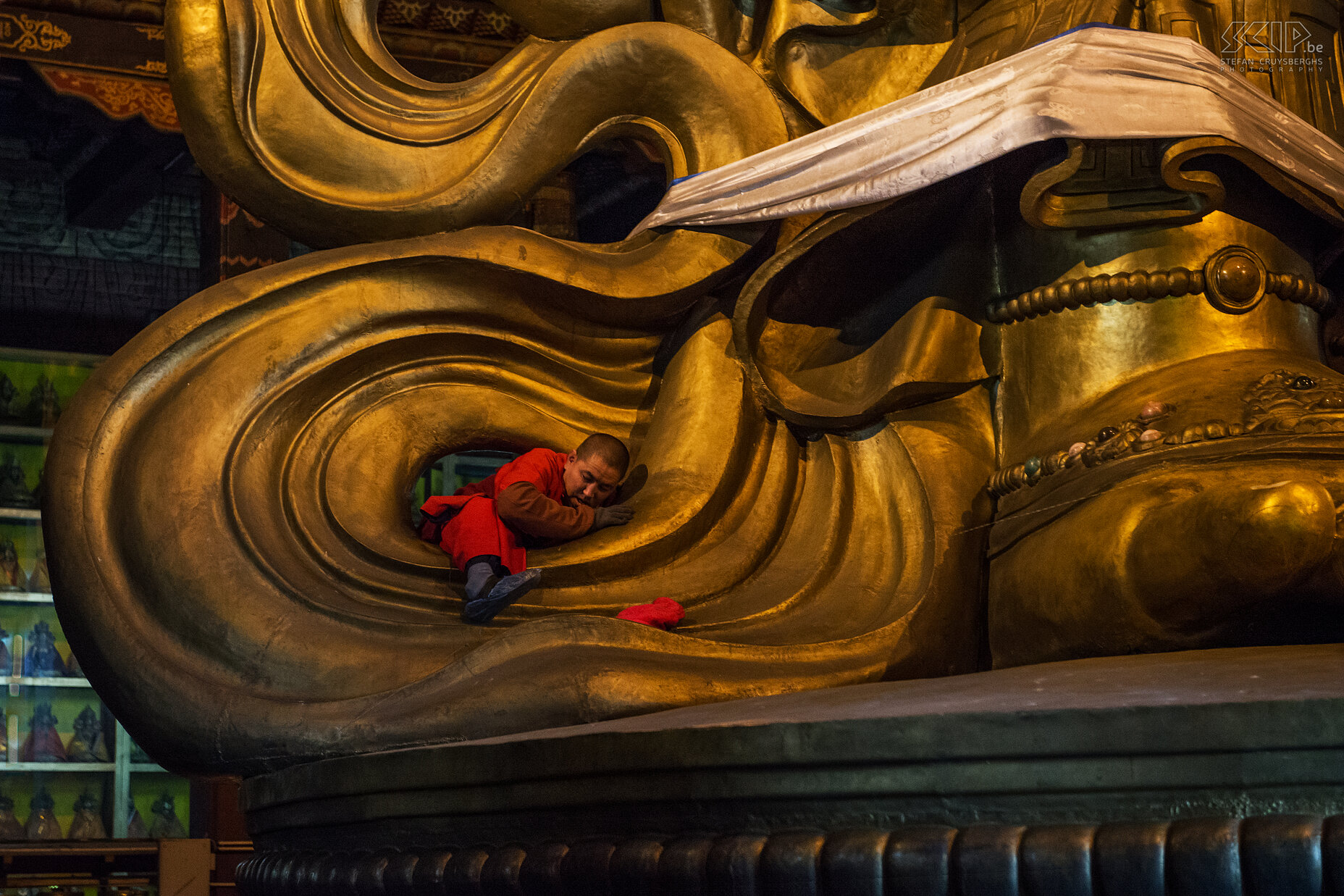 Ulaanbaatar - Gandan monastery - Monk A monk crawls through the statue to clean it at the back. Stefan Cruysberghs